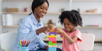 Mother and daughter building a colorful block tower together indoors.