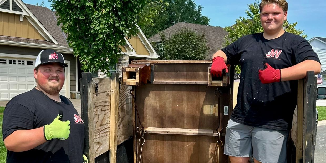 Two men posing with construction materials outside houses.