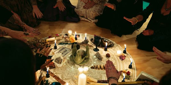 A group of people performing a ritual around a decorated altar with candles and symbolic objects.