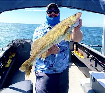 Man holding a large fish on a boat.