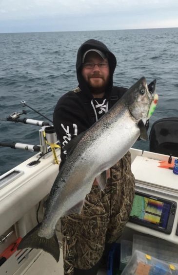 Man holding large fish on a boat.