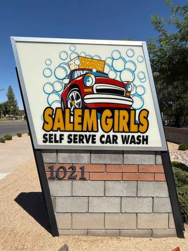 Colorful sign for Salem Girls Self Serve Car Wash featuring a red car and soap bubbles.
