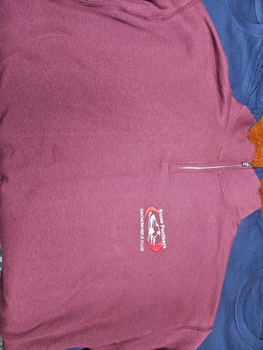 Maroon sweatshirt with a logo and zip collar.