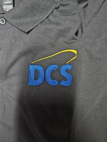 Black polo shirt with blue DCS logo and yellow swoosh.