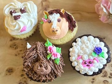 Four cupcakes showing a dog, horse, highland cow and sheep.