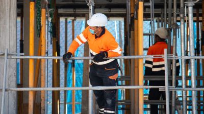 Two construction workers wearing safety gear on a building site.