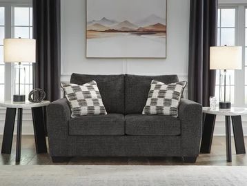 Modern gray loveseat with checkered pillows and matching lamps.