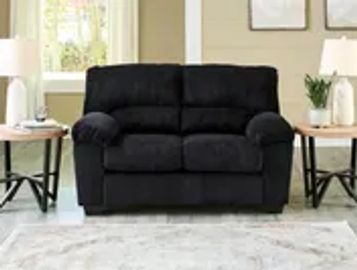 Black loveseat between two side tables.