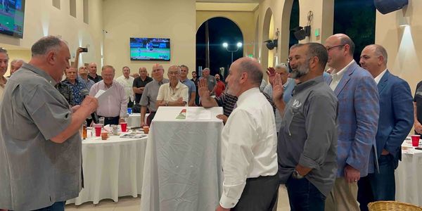 A group of men participating in a formal oath-taking ceremony indoors.