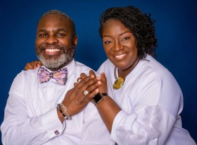 Smiling couple holding hands against a blue background.
