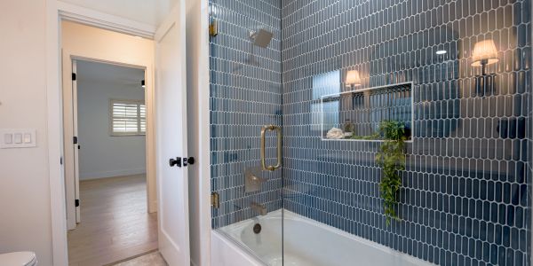 Modern bathroom with blue tiled shower and bathtub.