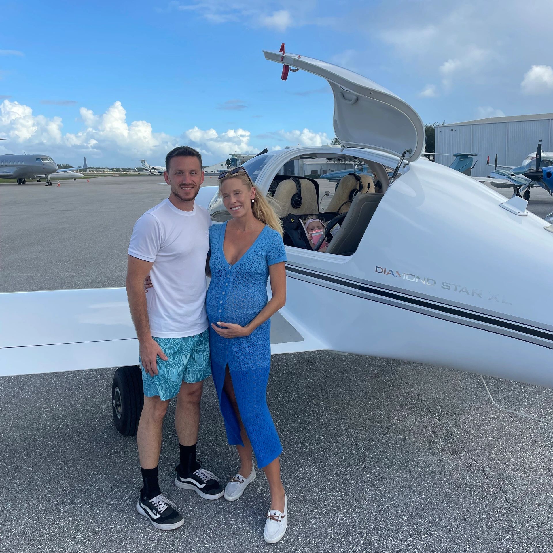 A couple standing next to a Diamond Star XL plane with a child inside.