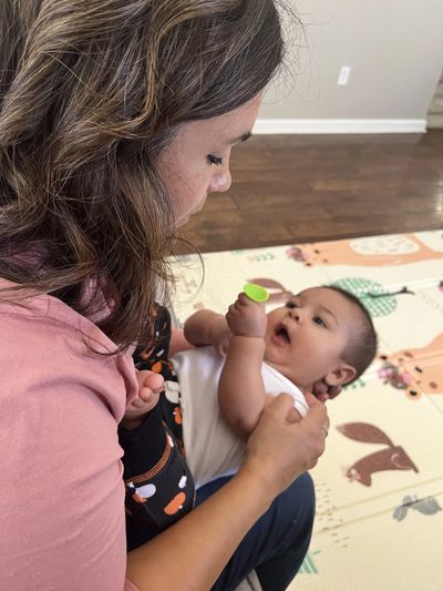 A woman holding and engaging with a baby indoors.