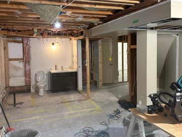 Basement under renovation with exposed ceiling and plumbing.