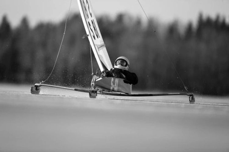 Person racing an iceboat on a frozen lake.