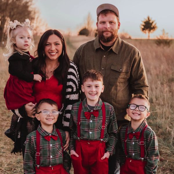 A happy family posing outdoors in coordinated festive attire during sunset.