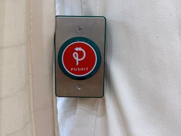 A red push button on a metallic plate with a white background.