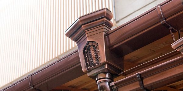 Copper gutters with fancy downspout drop-down covers.