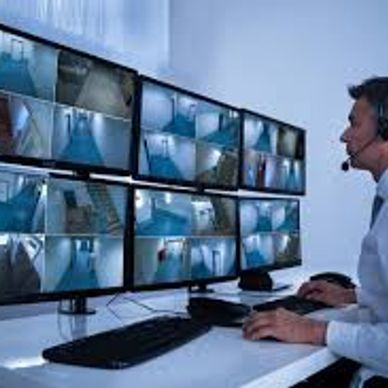 Man monitoring multiple security camera screens.