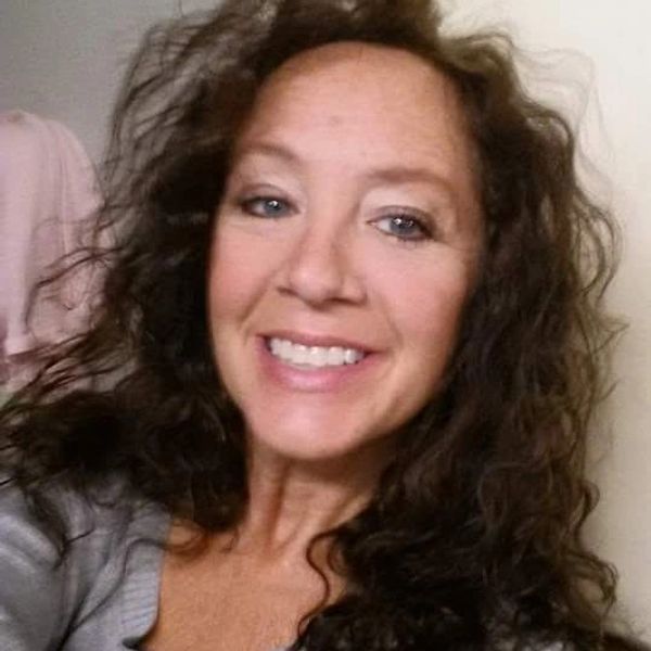 A woman with curly brown hair smiling at the camera.