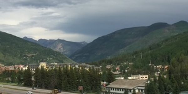 Mountain town nestled among green hills under a cloudy sky.