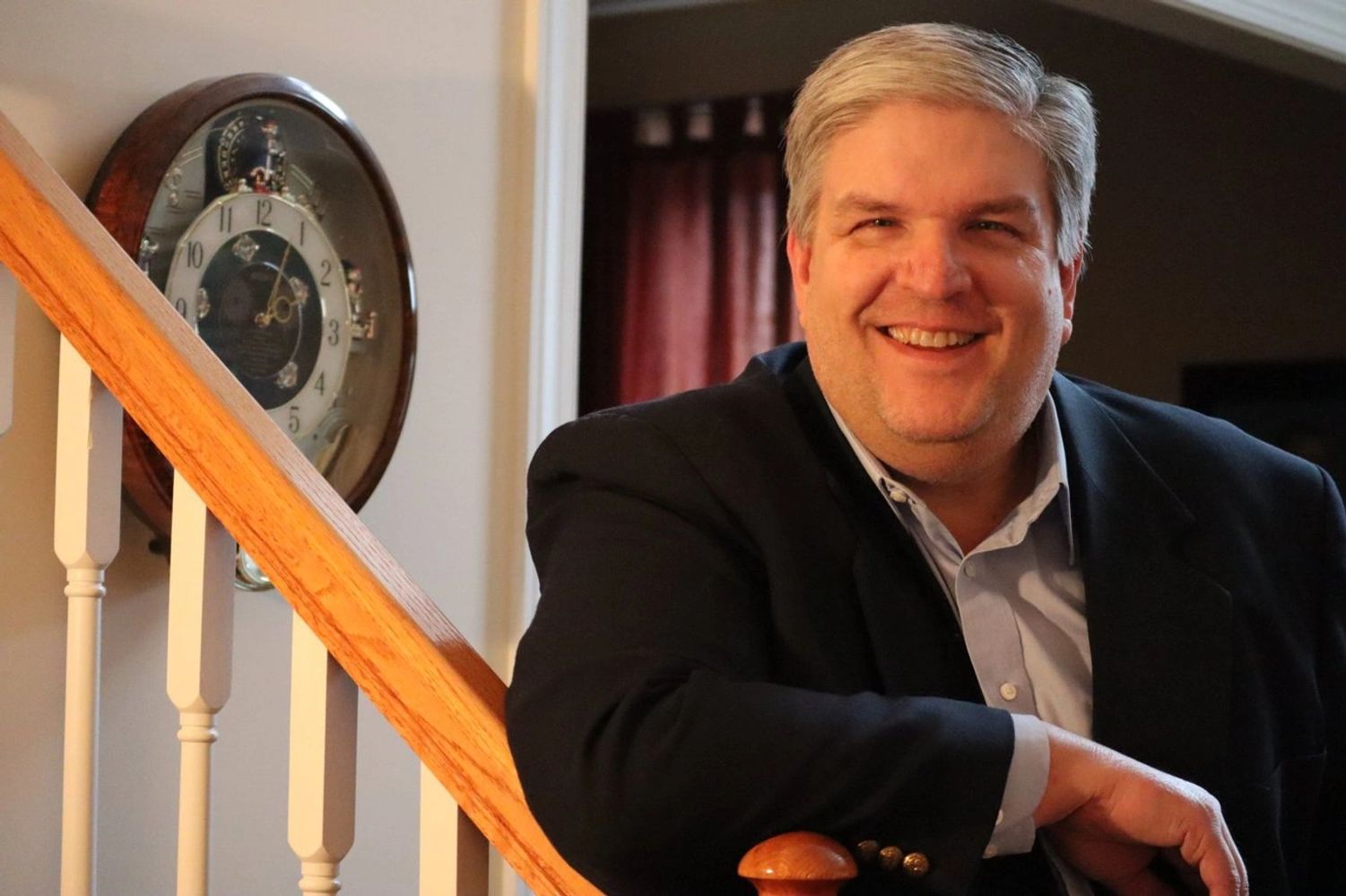 Man is business suit standing near a clock