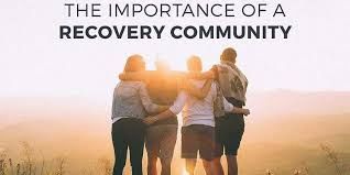 Group of four people embracing at sunset symbolizing recovery community support.