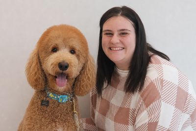 Happy woman with a curly-haired dog smiling together.