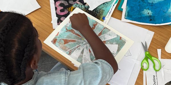 Child creating art with stencil and paint.