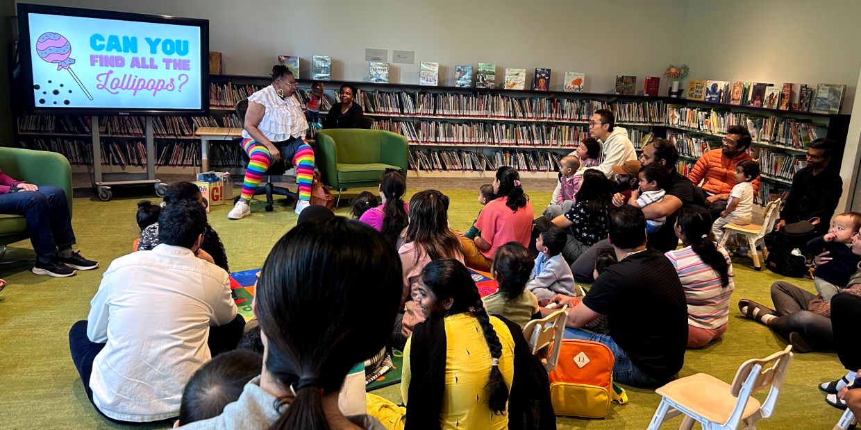 Children and adults attend a colorful storytime session in a library.