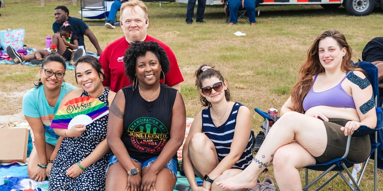 A group of diverse friends smiling outdoors on a sunny day.