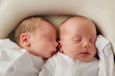 Two newborn babies sleeping peacefully side by side.