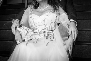 Black and white close-up of a bride and groom holding hands on stairs.