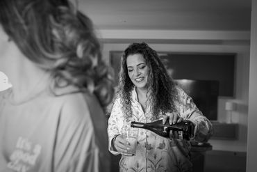 A woman happily pours a drink for another person indoors.