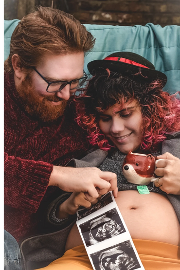 Couple looking happily at ultrasound images over pregnant belly.