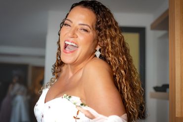 Joyful woman with curly hair laughing brightly indoors.