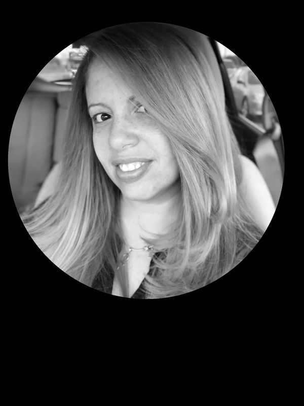 Black and white portrait of a smiling woman with long hair inside a car.