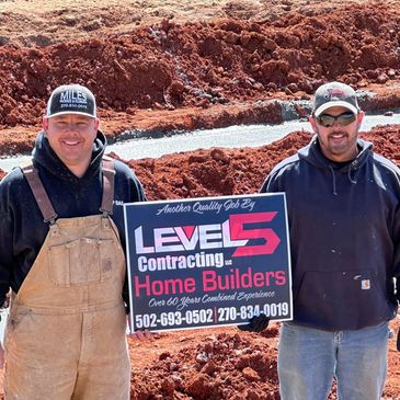 Two men holding a Level 5 Contracting Home Builders sign at a construction site.