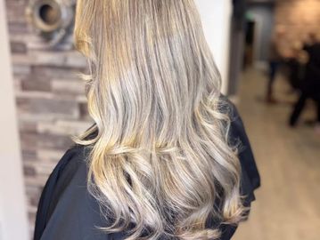 Long, wavy platinum blonde hair styled in soft curls.