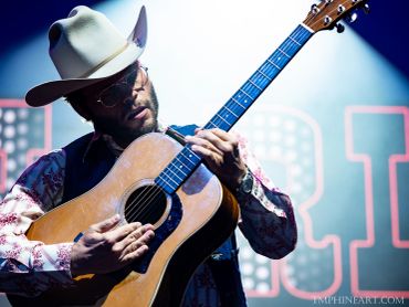Man playing acoustic guitar on stage.