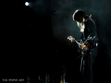 Silhouetted guitarist performing on stage with moody lighting.