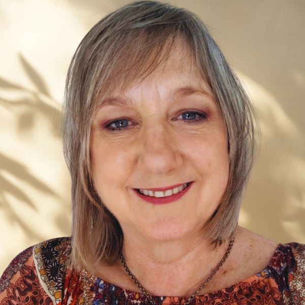 Smiling woman with short hair wearing a patterned top.