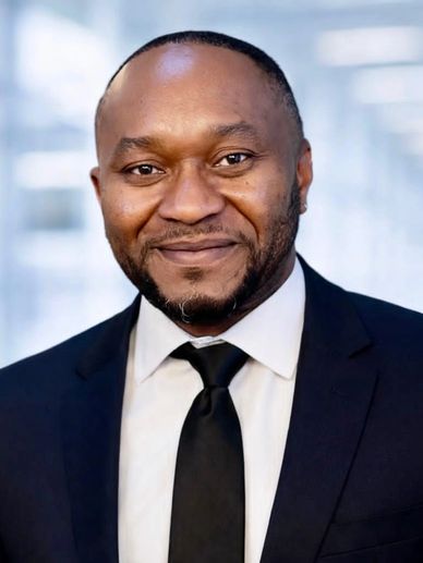 Smiling man in a suit and tie with a professional background.