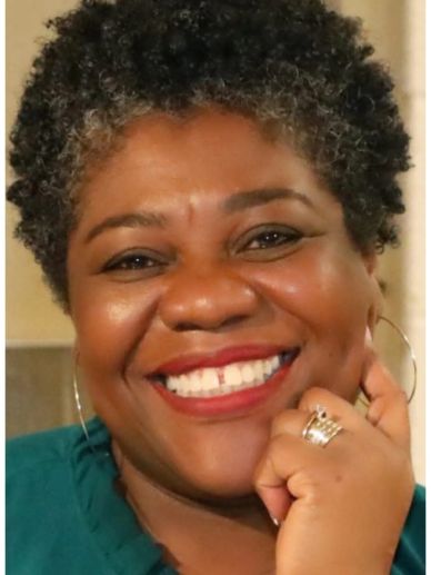 Smiling woman with short curly hair and hoop earrings.