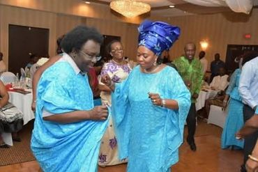 Two people in blue traditional attire dancing joyfully at a celebration.
