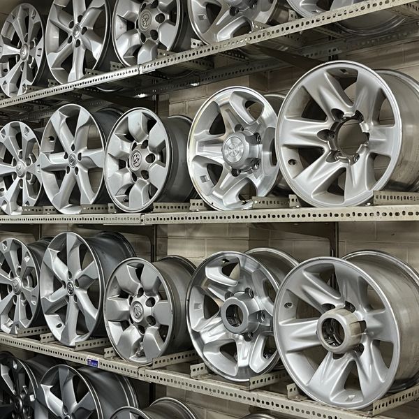 Rows of silver car rims on metal shelves.