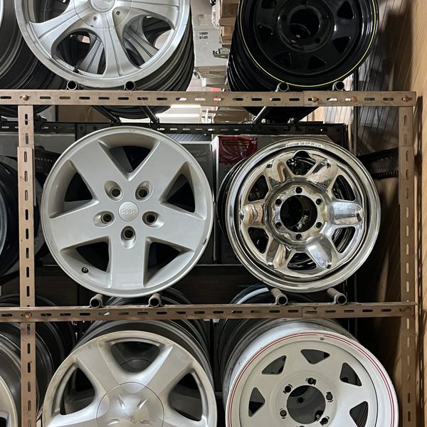 Six different car rims stacked on shelves.