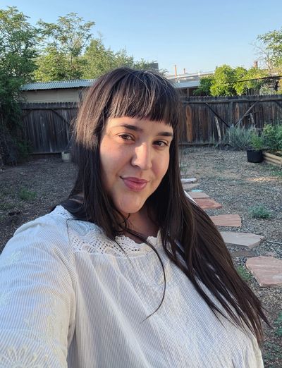 Woman taking a selfie outside in a garden.