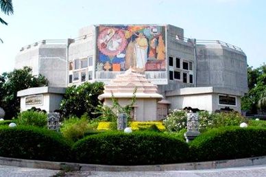 A historic museum building with a colorful mural and lush garden in front.