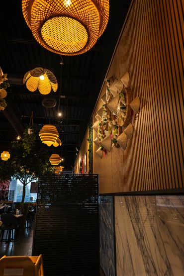 Warm, artistic lighting fixtures hang in a cozy, modern restaurant interior.